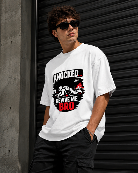 Person wearing a white t-shirt with a graphic design and text, standing against a dark metallic shutter.